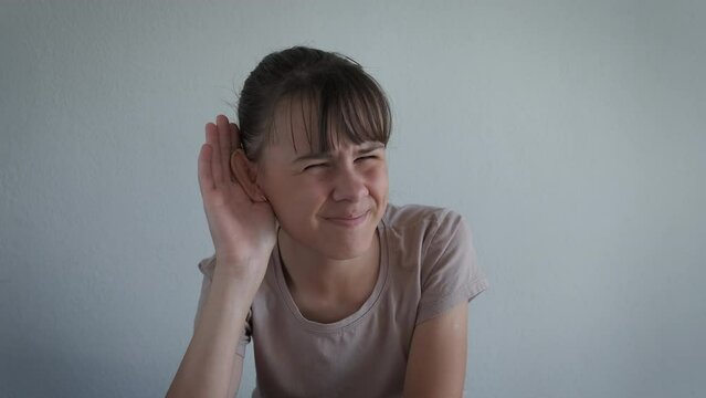 Put hand for better hearing. A teen with health problems try to hear better putting her hand by the ear in the room.