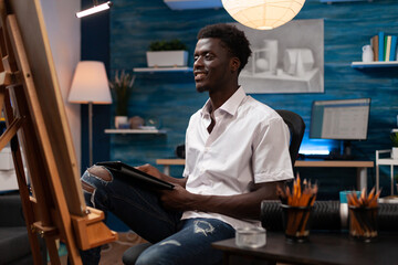 Young african american male cartoonist making digital copy of artwork with electronic tablet....