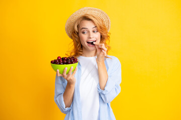 Picking eating cherry fruit. Portrait of woman with cherries on yellow studio isolated background.