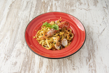 A delicious Italian sea pasta recipe with fat shrimp, prawns, clams and some other fish on a red plate