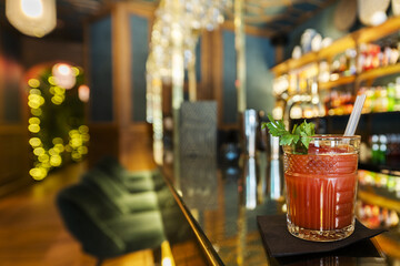 A glass of Bloody Mary served in a cut crystal tumbler on a shiny bar counter