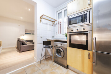 Detail of a kitchen without doors with wooden furniture and stainless steel appliances