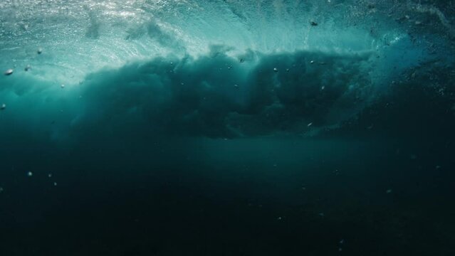 Pro surfer rides the wave, speed warp. Young man surfs the ocean wave in the Maldives and aggressively turns on the lip. Splitted above and underwater view with time warp effect