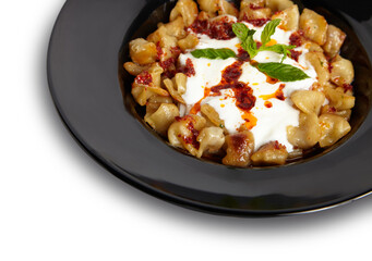 Turkish Dumplings (Mantı) in black plate isolated white background close up.