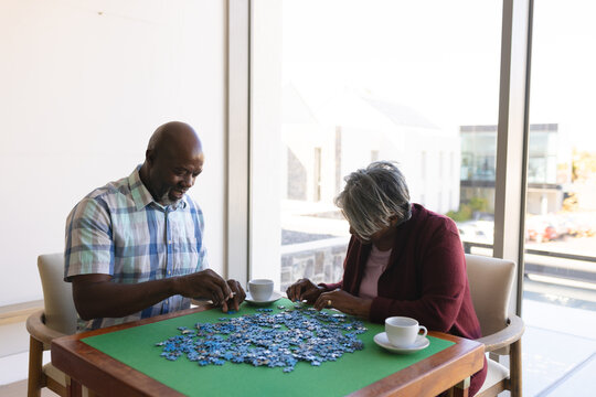 African american senior couple solving jigsaw puzzle at home