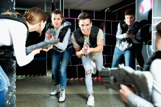 Cheerful Laser tag players young mens and womens playing in teams in dark laser tag station. High quality photo