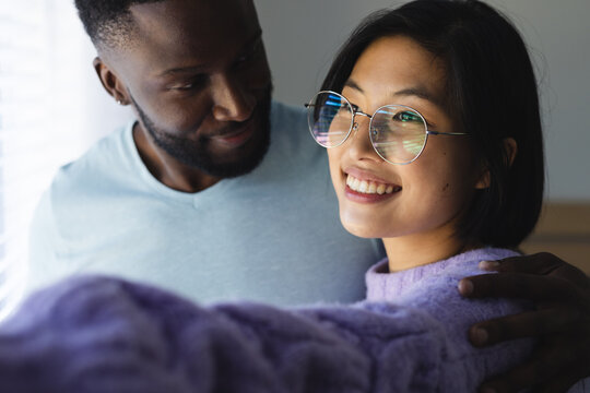 Happy diverse couple embracing and looking through window