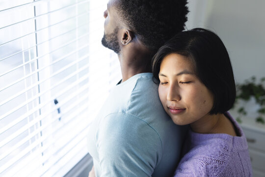 Happy diverse couple embracing and looking through window