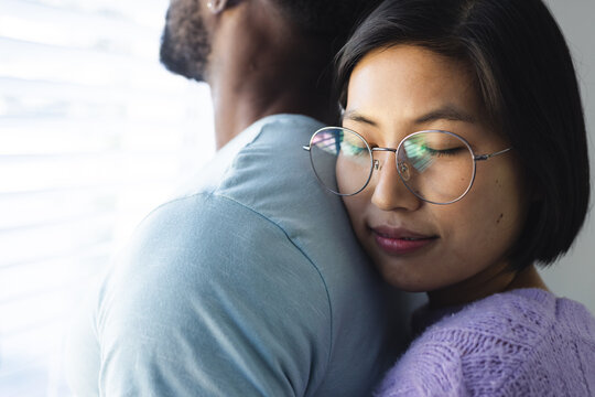 Happy diverse couple embracing and looking through window
