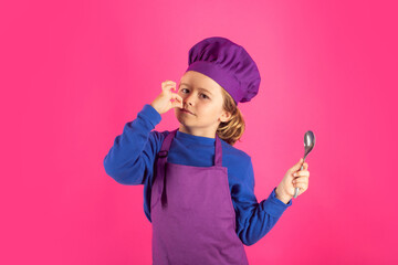 Funny kid chef cook with spoon. Chef kid boy making healthy food. Portrait of little child in chef hat isolated on studio background. Child chef. Cooking process.