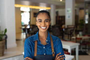 Portrait of happy biracial female barista wearing apron in cafe