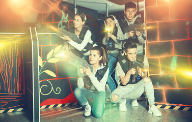 Group of young people with laser guns having fun in dark room