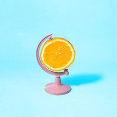 Fresh fruit concept. Orange slice as globe on pastel light pink background. Minimalistic juicy food composition. Creative summer nature idea.