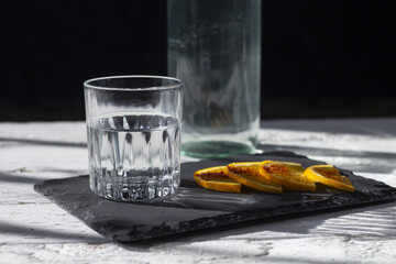 alcoholic drink like vodka, tequila or mezcal in fancy glass next to bottle and orange slices