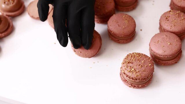 Process of making macarons macaroons, french dessert. chef hands in black gloves are assembling, connecting of two halves with chocolate stuffing at pastry shop. cooking, food and baking concept