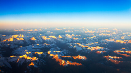 Winter aerial landscape of snow cap mountain in sunrise. Karakorum or Himalaya mountain from above in morning.Sunlight touch the peak of summit with clear blue sky.Mountain in Leh Ladakh,India.