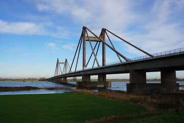 Fototapeta na wymiar Bridge with motorway the Willem Alexander bridge over the river Maas built on pillars and connecting land. Dutch bridge where industry ships pass under.