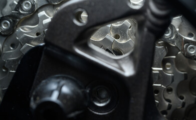 Detailed view through a bicycle derailer at a complex set of gear sprockets in shades of silver to gray.
