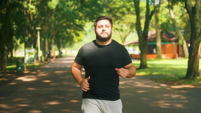 Front view following man jogging at the park on a sunny summer day slow motion	