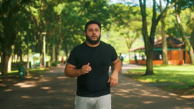 Focused overweith guy jogging outdoors at a park