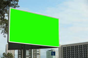 Chroma key compositing. Big empty billboard with green screen in city. Mockup for design