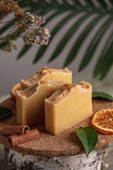 Piece of natural soap and slices of oranges, cinnamon and green leaves on the wooden table. Concept of eco soap and interesting hobby