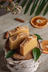 Natural soap and slices of orange, cinnamon and green leaves on the wooden table. Concept of eco soap and interesting hobby