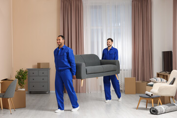 Male movers carrying sofa in new house