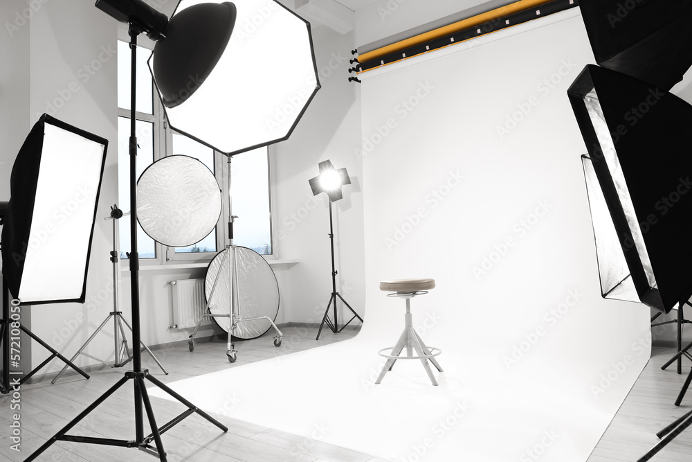 Poster interior of modern photo studio with bar stool and professional lighting equipment