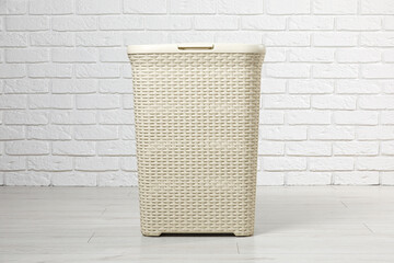 Empty laundry basket near white brick wall