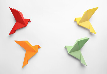 Origami art. Colorful handmade paper birds on white background, flat lay. Space for text