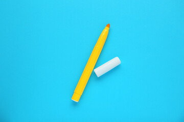 Bright yellow marker and cap on light blue background, flat lay