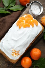 Delicious homemade yogurt cake with tangerines and cream on wooden table, flat lay