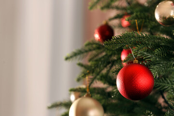 Christmas tree with beautiful baubles on blurred background, closeup. Space for text