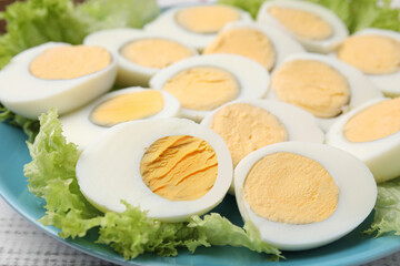 Fresh hard boiled eggs and lettuce on white wooden table, closeup