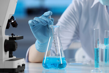 Fototapeta premium Scientist taking sample of light blue liquid, closeup