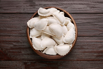 Raw dumplings (varenyky) on brown wooden table, top view