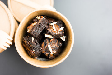 Chocolate mini brownies with slice of nut and chocolate chips in brown paper box