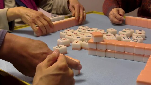 Close up of anonymous women's hands playing Chinese mahjong at home