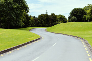 asphalt road winding through green field