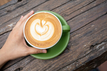 Heart shaped coffee with hand about to drink