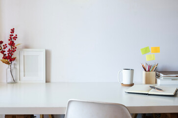 Comfortable workplace with books, picture frame, retro camera and coffee cup on white table. Copy space for text.