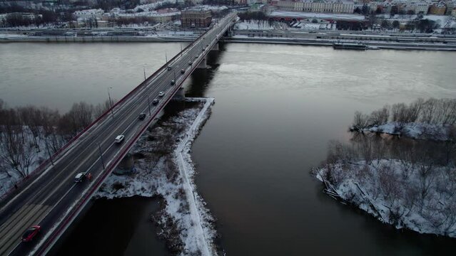Aerial tracking shot of vehicle crossing Vistula River during snowy day in Warsaw City,Poland - Tilt up