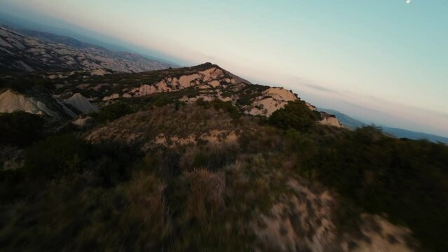Hilly landscape of Calanchi di Aliano in Italy during sunset. Drone FPV shots