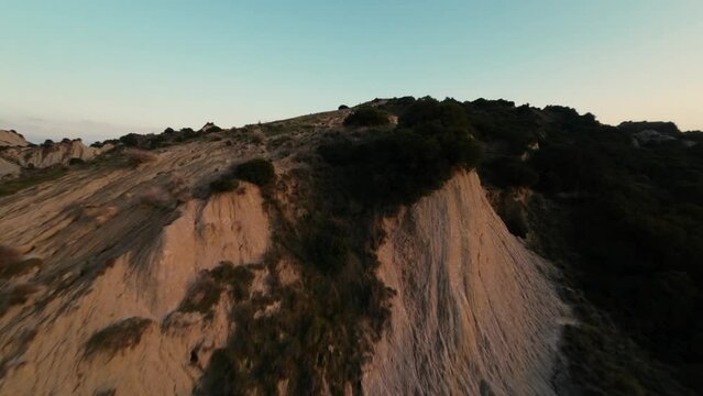 Fast FPV drone shot over the hilly landscape of Calanchi di Aliano in Italy during sunset. 