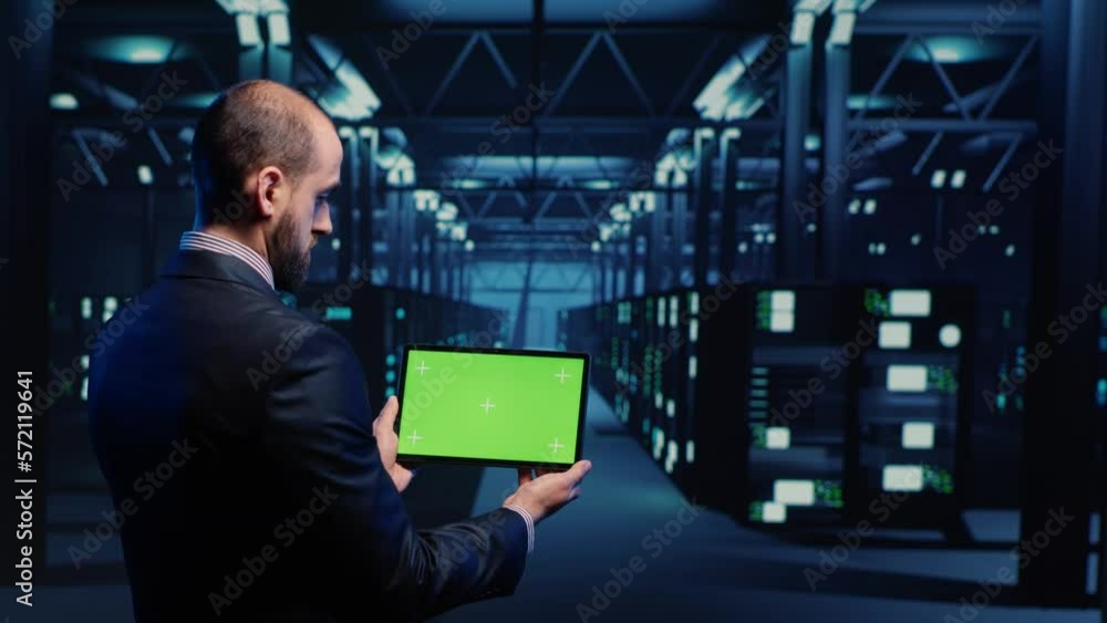 Poster system engineer checking green screen display on tablet, running mainframe diagnostics in data cente