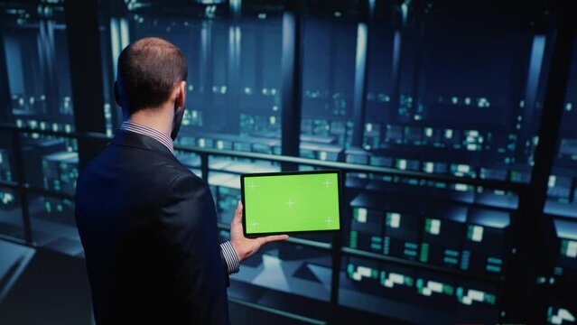 Support specialist using tablet with greenscreen display in modern data center, checking blank chroma key template. Database admin working with isolated mockup and hardware industry. Tripod shot.
