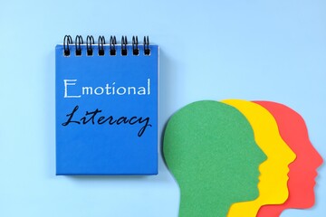 Emotional literacy concept. Word written on blue notepad with human head profile silhouette.
