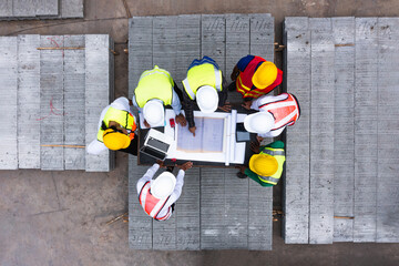 Aerial top view of architect and engineer discussing building plan at table and his blueprints on...