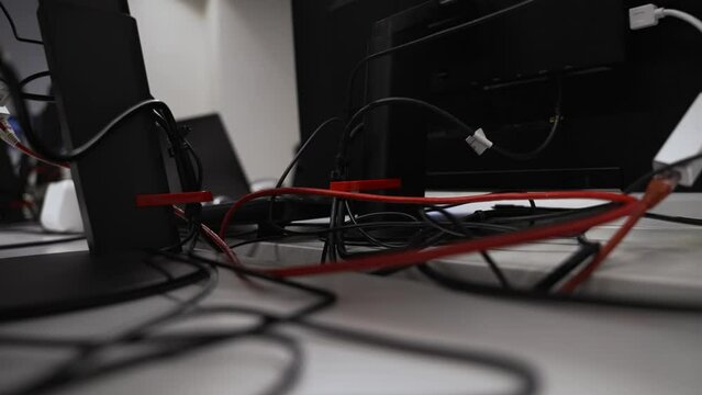 Close Up Behind Computer Monitor Stand Of Cables, Ethernet, Power Leads. Slow Motion Pan Right, Low Angle
